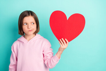 Photo of brunette hairdo unsure little girl hold look paper heart wear pink sportswear isolated on teal color background