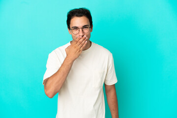 Caucasian handsome man over isolated blue background happy and smiling covering mouth with hand