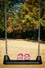 Pink sandals child on swing in the park.