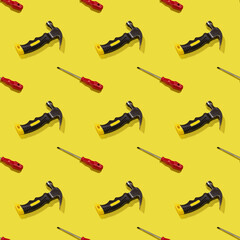 Hammers and screwdrivers on a yellow background, pattern, hard shadows. Construction tools, repairs. Background for the design.