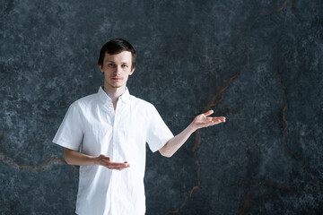 Studio portrait of young man wearing white shirt pointing with hands and explaining something to audience