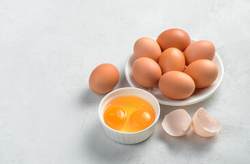 Chicken eggs and raw yolks on a gray background.