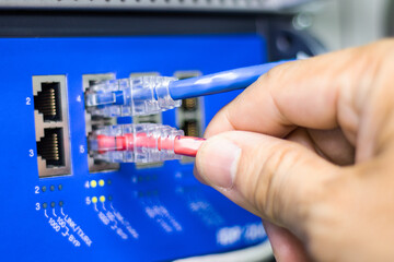 Hand of a man holding The network cables to connect the port of a switch to connect internet network, concept Communication technology