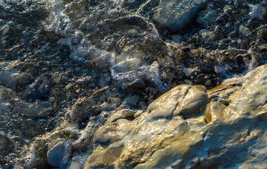 pebble stones on the sea beach, the rolling waves of the sea with foam