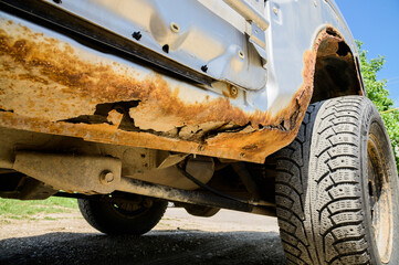 Fragment of a car body with rust. fragment of a rusty wing of a car. The body element is corroded....