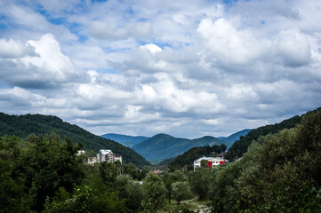 Fototapeta na wymiar Resort village in mountain valley against the blue sky with clouds, summer landscape