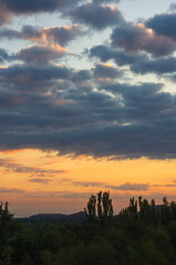 Landscape with dramatic light - beautiful golden sunset with saturated sky and clouds.