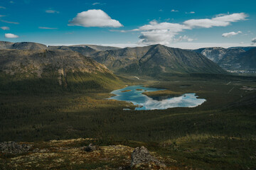 Beautiful blue lake with a reflection of the sky in valley on the background mountain picks  in cloudy weather in polar summer, top view. Arctic, Kola Peninsula 
