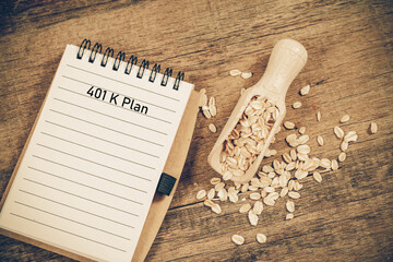 401 k Plan text on booknote with oats in spoon on wood table.