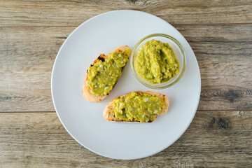 Avocado toasts with egg and shrimp on white plate on wooden table background
closeup.