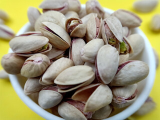 pistachio nuts in a bowl on yellow background