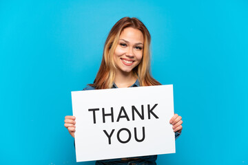 Teenager girl over isolated blue background holding a placard with text THANK YOU with happy expression