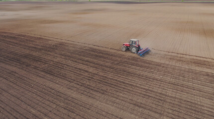 Aerial view of the tractor in the field, agricultural field work, sowing work in the field at sunset