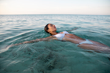 Model in swimsuit resting in pure ocean