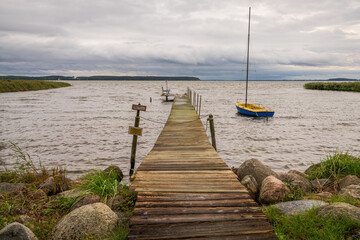 A wooden pier with a boat and some benches on the coast of the Krumminer Wiek in Neeberg, Mecklenburg-Western Pomerania, Germany