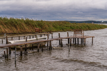 A wooden pier with a boat and some benches on the coast of the Krumminer Wiek in Neeberg, Mecklenburg-Western Pomerania, Germany