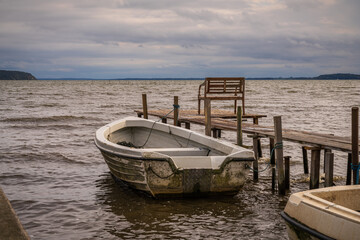 A wooden pier with a boat and a bench on the coast of the Krumminer Wiek in Neeberg,...