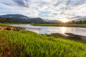selective focus light green grass by the river mountain landscape sunset fog clouds after mountain rain clear sky river light green grass giving a cool, refreshing feeling in the background