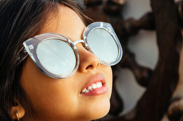 Happy little girl with big sunglasses looking at the sun.