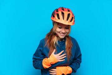 Young cyclist girl isolated on blue background smiling a lot