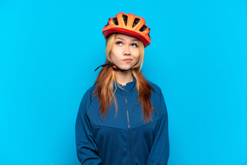 Young cyclist girl isolated on blue background and looking up
