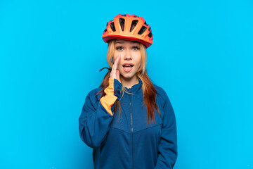 Young cyclist girl isolated on blue background with surprise and shocked facial expression