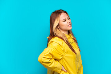 Fototapeta premium Teenager girl wearing a rainproof coat over isolated blue background suffering from backache for having made an effort