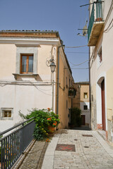 Fototapeta na wymiar Candela, Italy, 06/21/2021. A small street between the old houses of a mediterranean village of Puglia region.