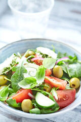 Summer Salad with Cream Cheese, green Olives, Tomatoes and fresh Basil. Bright wooden background. Close up. 