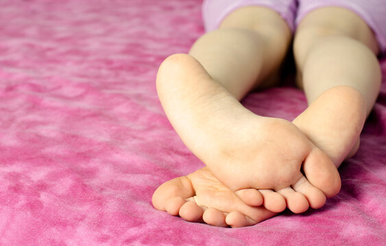Children with bare feet. Lie on the bed. In the room.