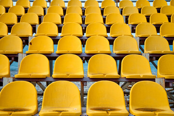 Naklejka premium Yellow plastic seats on the podium of a small sports field