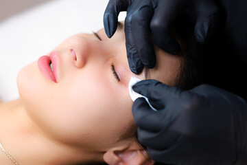 a master of lamination of cilia, his hands pull the client's eyelids in close-up and clean them...