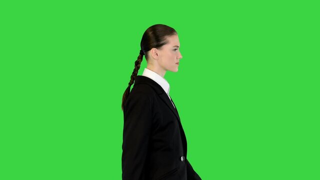 Young woman in office suit walking, adjusting her jacket on a Green Screen, Chroma Key.