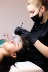 the girl of the master of lamination of eyelashes sits at the head of the client and prepares for the lamination procedure