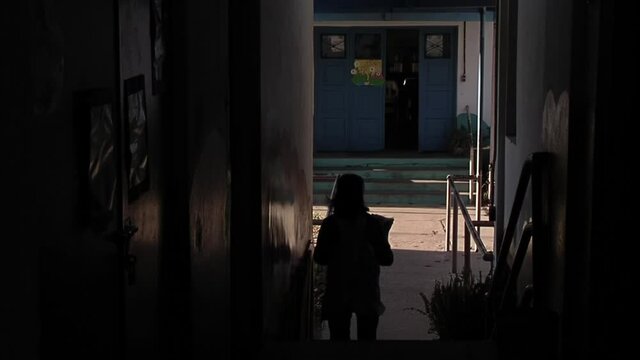 Silhouette of a Female Teacher walking Down Stairs at Dark Corridor in a Public School in Tigre, Argentina. 