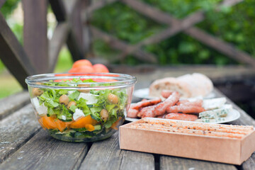 Fresh healthy salad with olives and feta chees on wooden table. Baked cookies and bread with...
