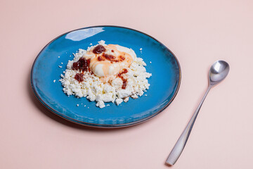 Blue plate with cottage cheese and jam on a pink background. Morning breakfast concept.
