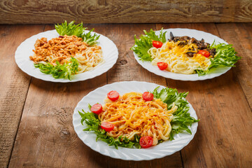 Three plates with different pasta on a wooden table.
