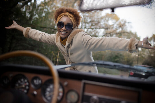 Portrait excited young woman in sunglasses outside convertible