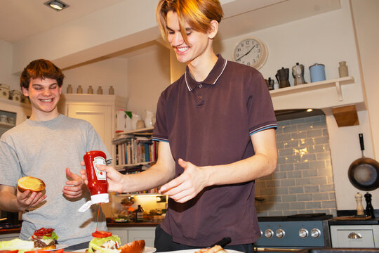 Teenage boys preparing hamburgers in kitchen