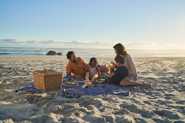 Family enjoying picnic lunch on sunny ocean beach