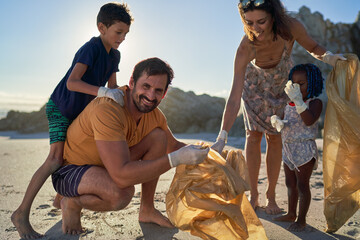 Portrait happy family picking up garbage on sunny beach