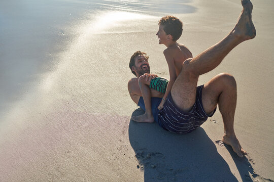 Happy father and son playing on sunny ocean beach