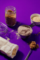 Baking ingredients and utensils on purple background