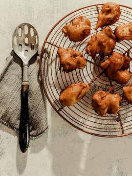 Fried fritters on cooling rack with slotted spoon and gray napkin