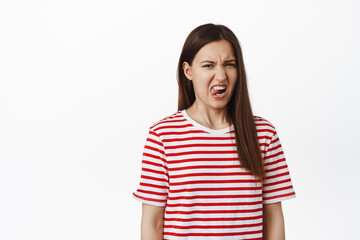 Disgusting. Young 20s girl student express dislike or aversion, show tongue, grimacing and...
