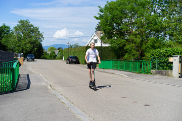 Naklejka premium 17 year old boy on an electric scooter.