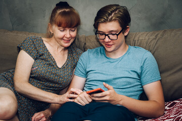 Home photo teen son listens to mom sitting on the sofa right in front of the camera