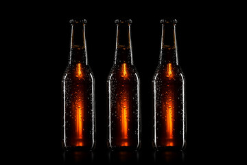Small brown beer bottle with drops on black background
