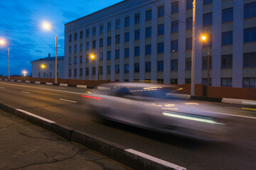 Fototapeta premium Motion of a blurred car along the overpass in the evening.